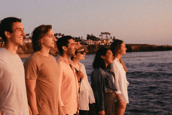 a group of people standing next to a body of water