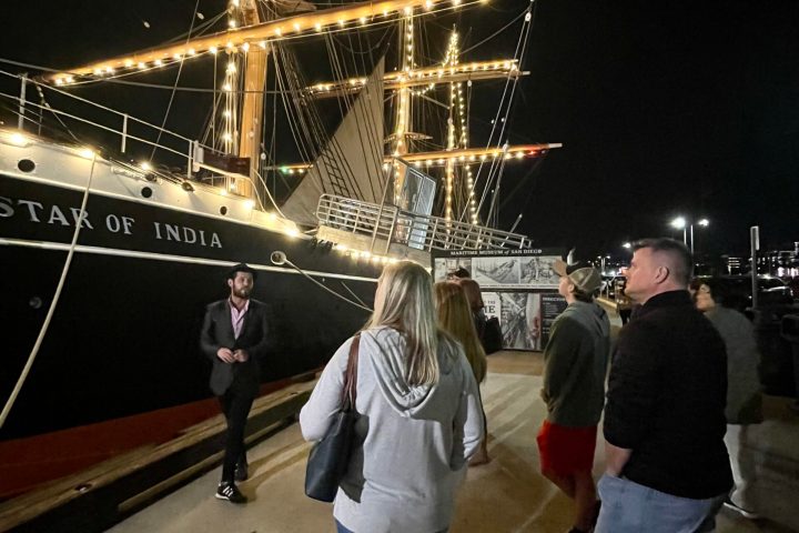 a group of people standing in front of a large ship in the background
