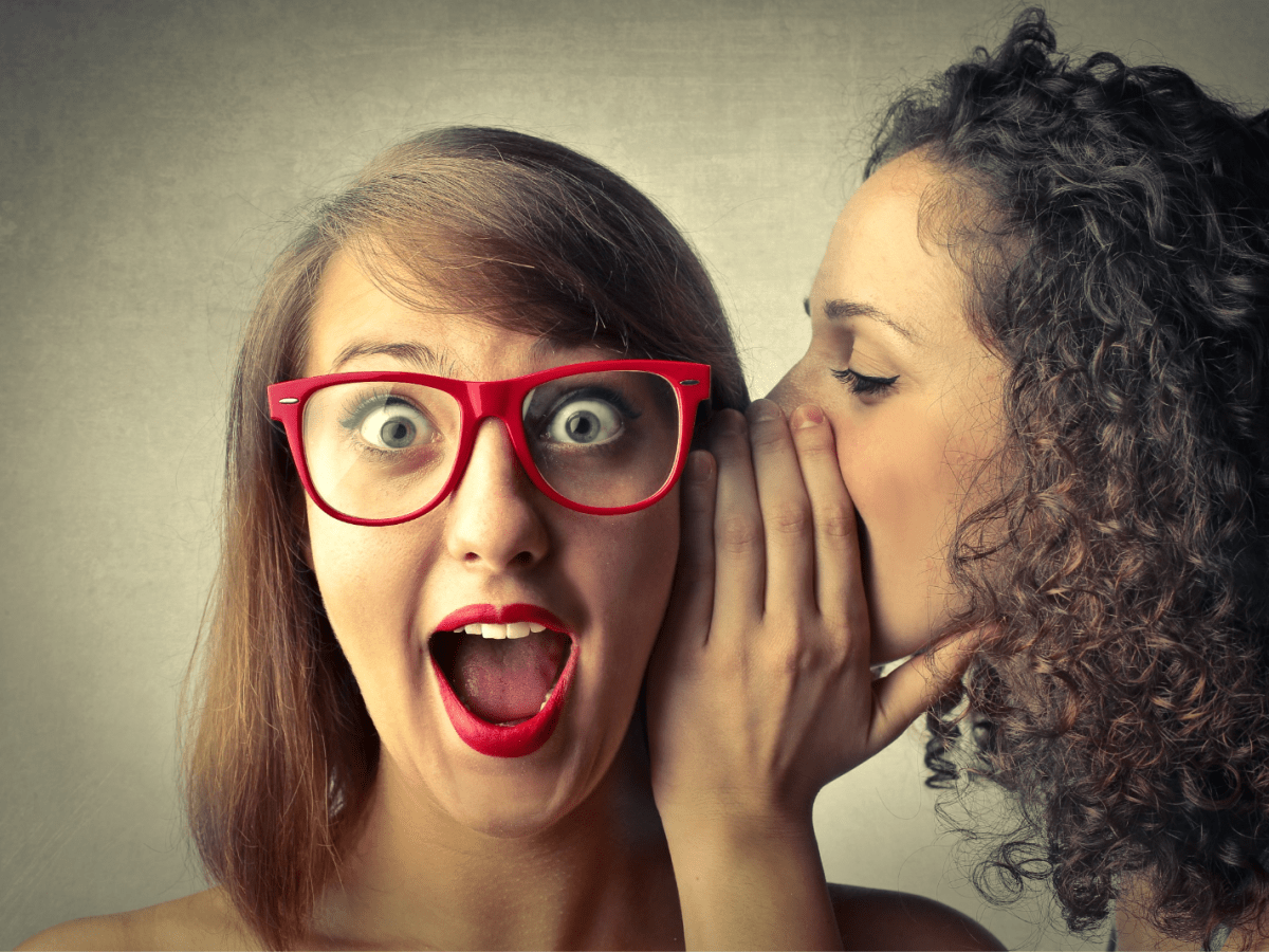 a person wearing glasses being told a secret